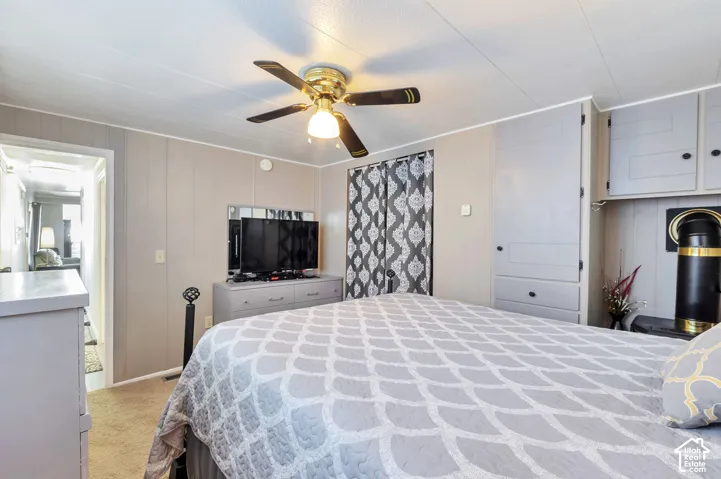 Recessed built-in cabinetry, ceiling fan with integrated lighting, paneled walls, and carpeted flooring