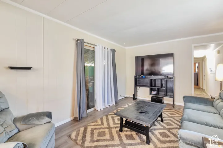 Living area featuring wood-finish flooring, vertical paneling, and a sliding glass door