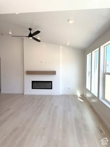 Vaulted ceiling with recessed lighting, electric fireplace and ceiling fan.