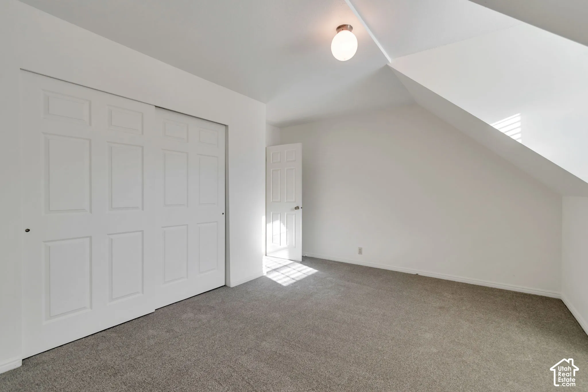 Sliding panel closet doors, neutral wall paint, overhead flush-mount light fixture, and gray carpet flooring