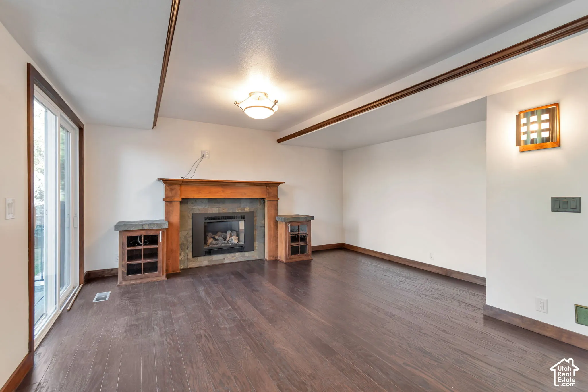 Wood-finish flooring, built-in fireplace with stone surround, wood mantel, built-in cabinetry, and sliding glass door