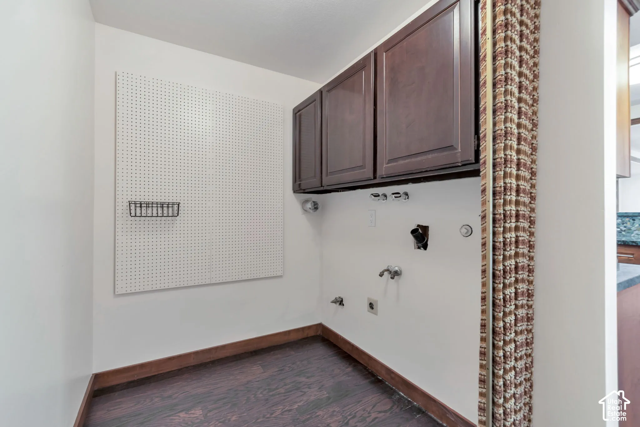 Built-in cabinetry, wood-finish flooring, and a pegboard wall