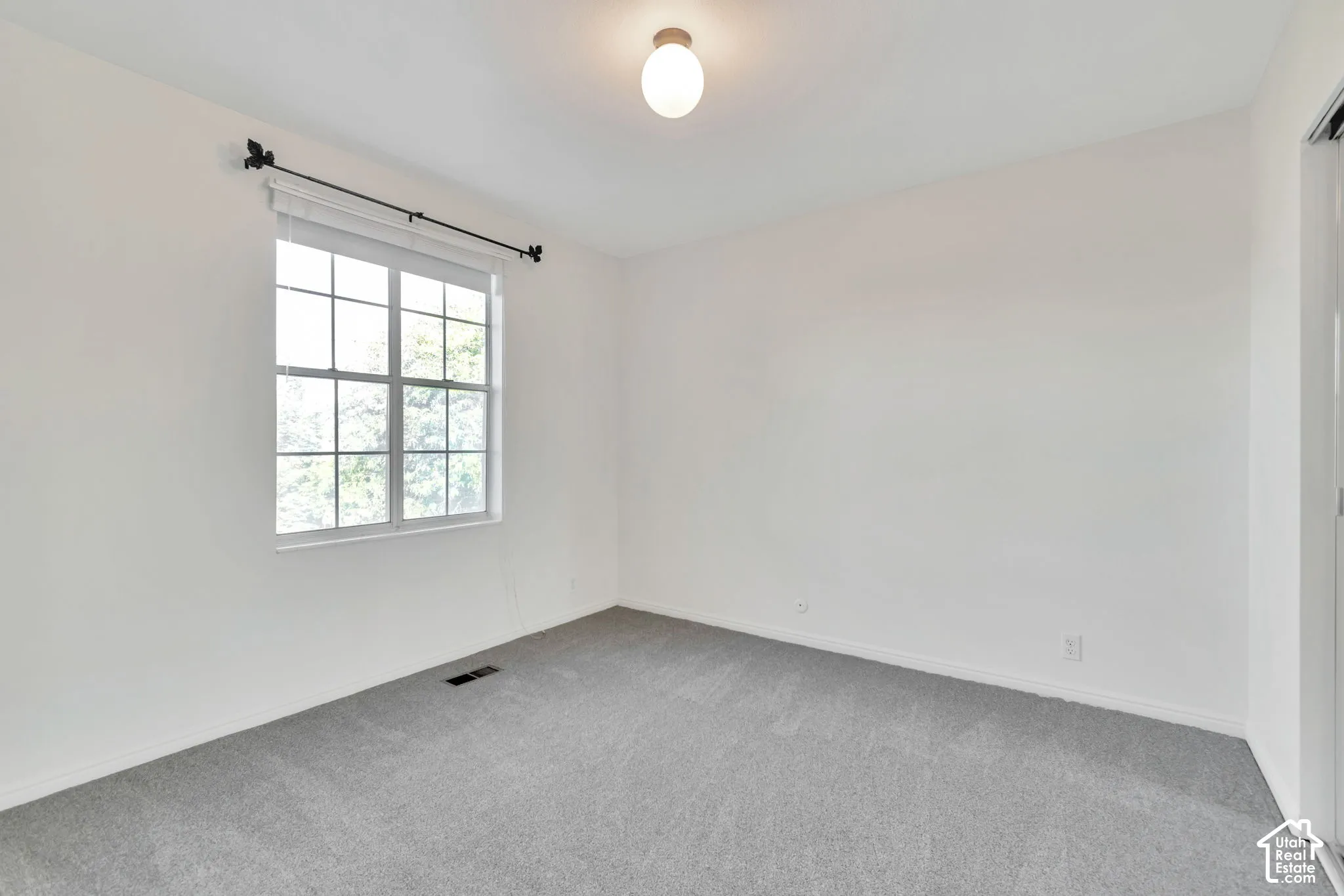 Carpeted room with a double-hung window, flush-mount ceiling light, and white painted walls