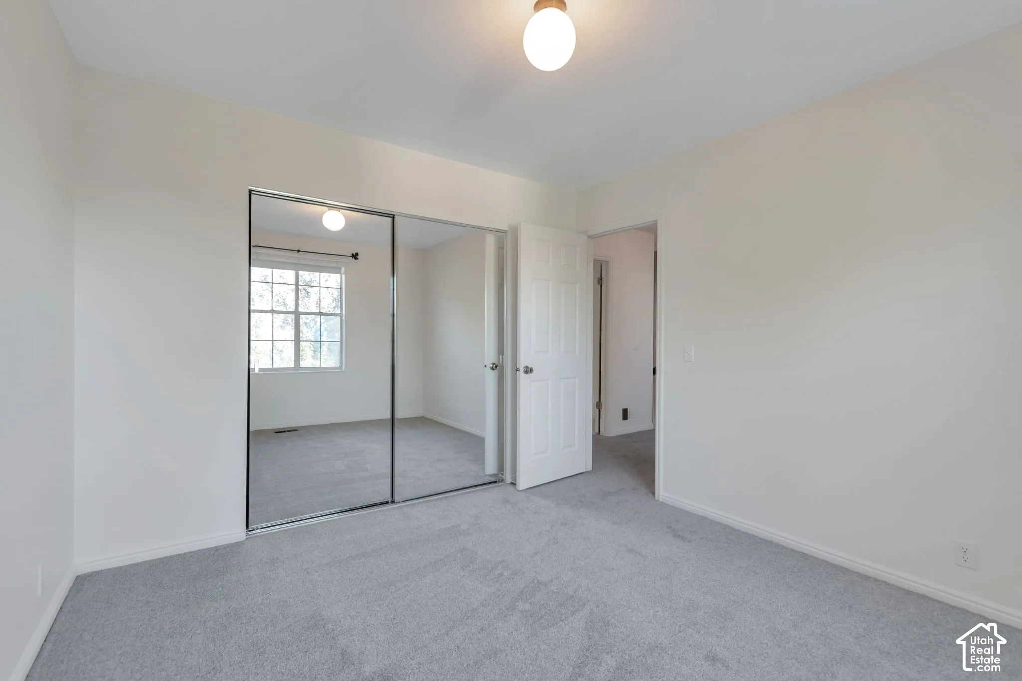 Plush grey carpeting, white interior doors, and a ceiling-mounted light fixture