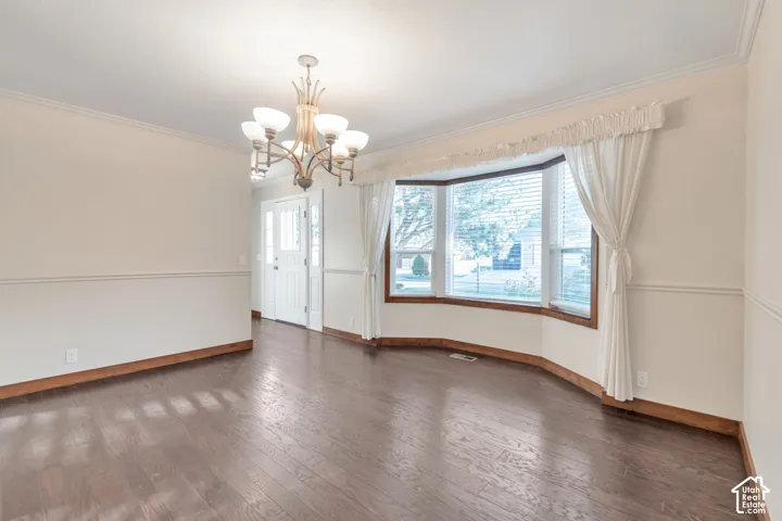 Wood-finish flooring, bay window, chandelier light fixture, and crown molding