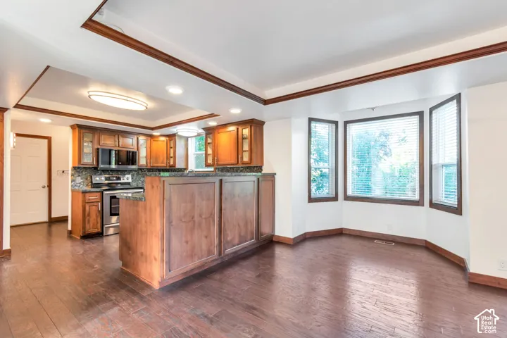 Kitchen with wood-finish flooring, recessed lighting, wood cabinetry, and stainless steel appliances