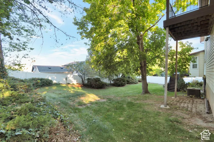 Expansive backyard featuring a manicured lawn, mature trees, and established shrubbery