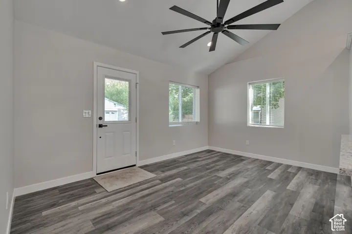 Vaulted ceiling, wood-finish flooring, two windows with blinds, recessed lighting, and a contemporary black ceiling fan
