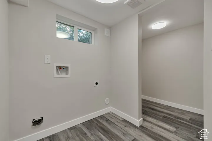 Utility room with storage room, wood-finish flooring and integrated lighting