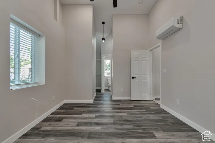 High ceilings with recessed lighting, wood-finish flooring, and a wall-mounted mini split unit.