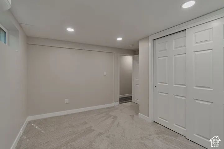 Recessed lighting, light-toned carpeting, neutral wall finishes, white trim, and a window well