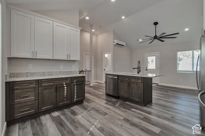 Open-concept kitchen with two-tone cabinetry, Granite countertops, stainless steel appliances, and a vaulted ceiling with a modern ceiling fan