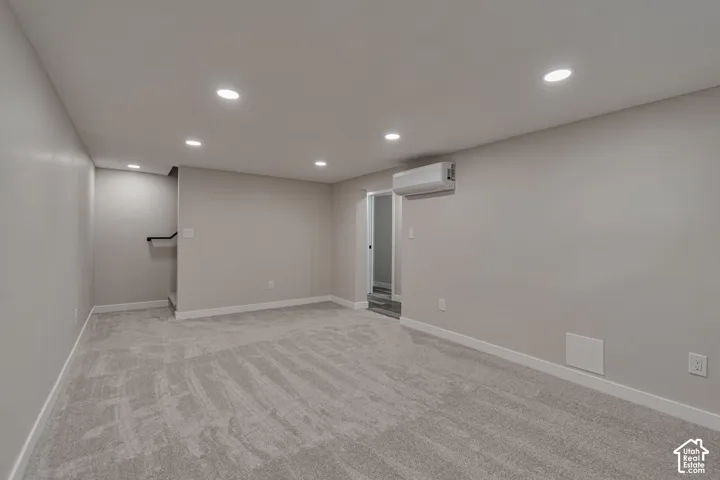 Recessed ceiling lighting illuminates a carpeted room with light-toned walls