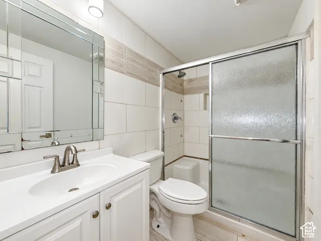 Bathroom featuring a white vanity with integrated sink, brushed nickel faucet, a beveled mirror, and a shower with sliding frosted glass doors