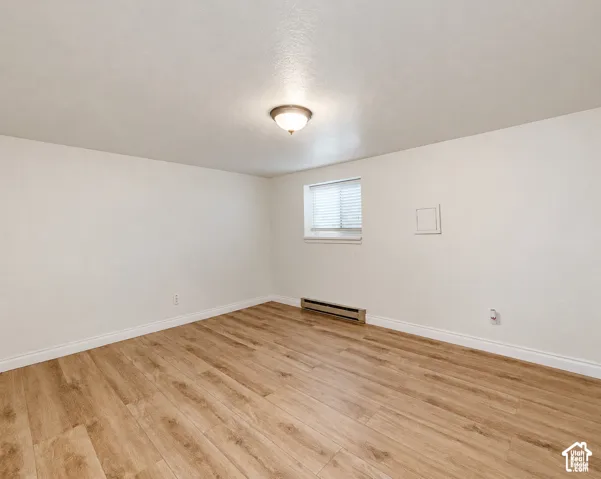 Wood-finish flooring, white walls, and a window with blinds