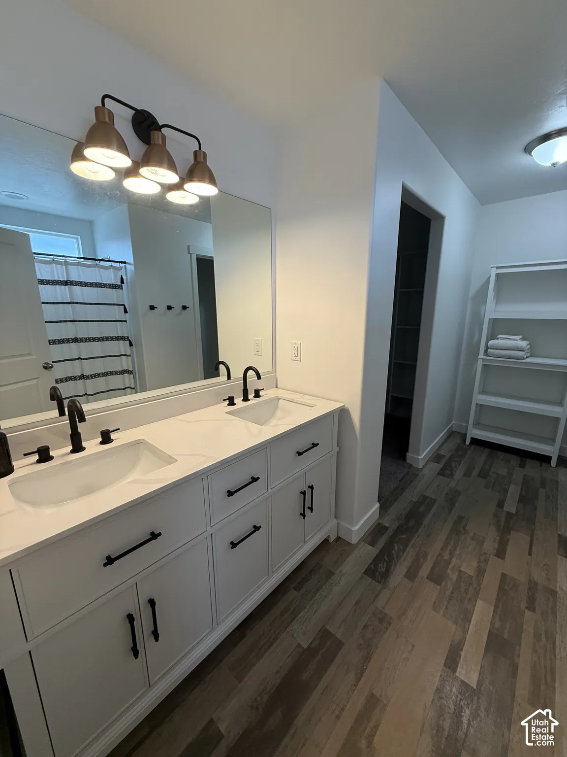 Dual vanity with integrated sinks and white countertops, matte black faucets, and wood-finish flooring