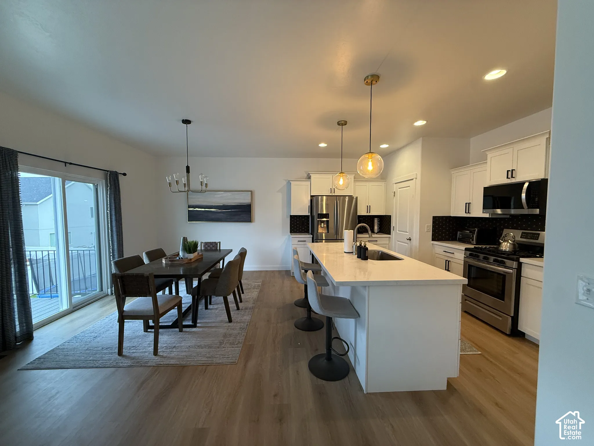 Open-concept living space with wood-finish flooring, a contemporary dining chandelier, and recessed lighting