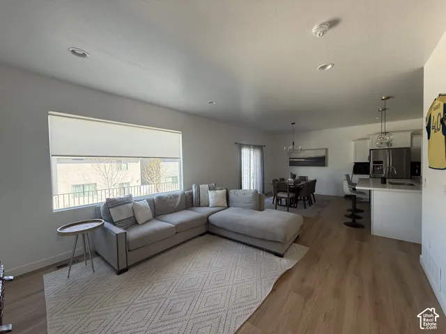 Open-concept living space featuring wood-finish flooring, recessed lighting, a large window, a dining area, and a kitchen with stainless steel appliances