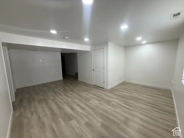 Spacious room with wood-finish flooring, recessed lighting, and crisp white walls