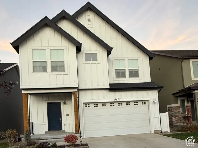 Two-story residence featuring white vertical siding and dark-trimmed gable roofs