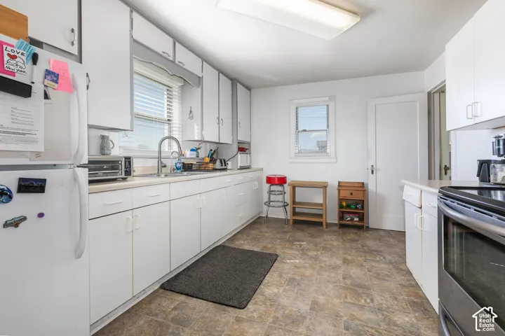 Kitchen featuring extensive white cabinetry, a single basin stainless steel sink, light-toned countertops, and durable wood-finish flooring