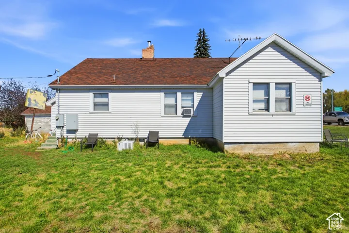 White horizontal siding exterior with a brown shingle roof, featuring a brick chimney and multiple windows