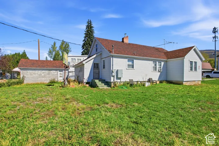 Spacious lawn area with a detached garage and a white siding exterior