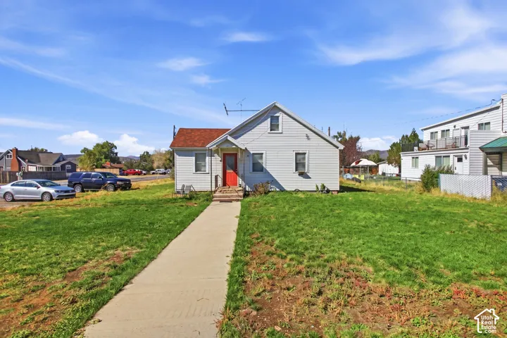 Single-story residence featuring white siding and a prominent red entry door