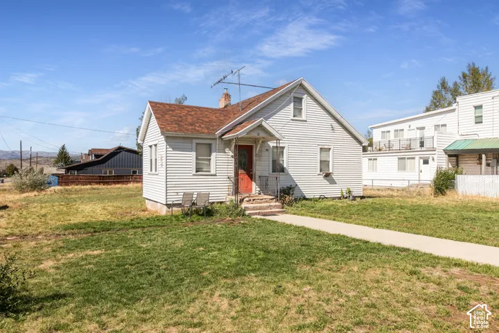 White siding exterior with a red entry door, gabled roofline, and visible chimney