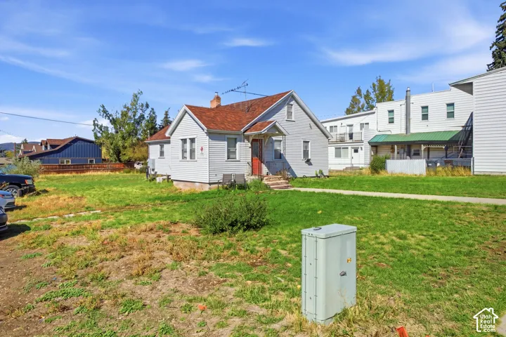 Charming home situated on expansive grounds featuring a generous lawn with mature landscaping, multiple outbuildings including a red barn structure, and established vegetation throughout the property