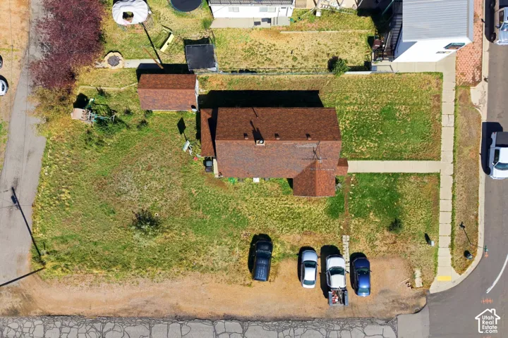 Property featuring a main residence with a brown shingle roof, an additional detached structure, a paved driveway, and a front yard with established landscaping