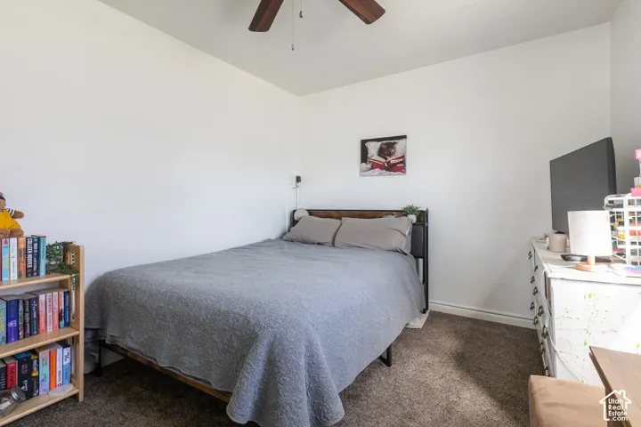Wall-to-wall carpeting with light-toned walls, featuring a ceiling fan with wood-finish blades
