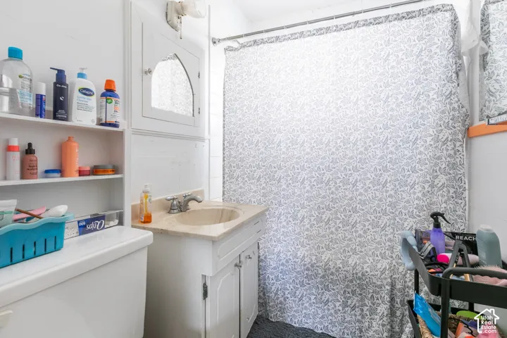 Bathroom featuring a vanity with a light-toned countertop, a built-in wall cabinet with an arched mirror, and a wall-mounted shelving unit