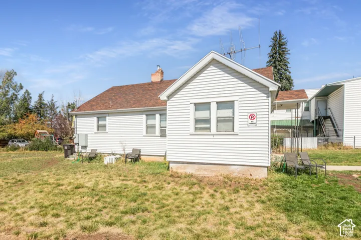 White horizontal siding exterior with a brown shingled roof and visible chimney