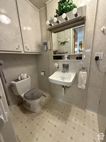 Efficiently designed bathroom featuring a ceramic tile surround, pedestal sink with chrome faucet, mirrored medicine cabinet with shelving, and hexagonal tile flooring