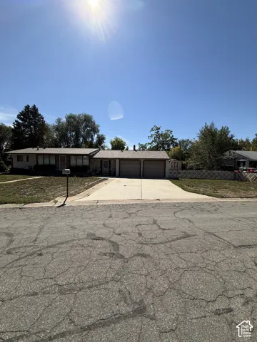 Single-story residence featuring a two-car attached garage, a paved driveway, and established landscaping