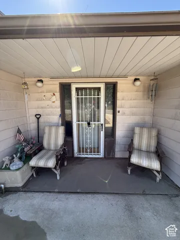 Covered entryway with concrete flooring, security screen door, and exterior wall lighting