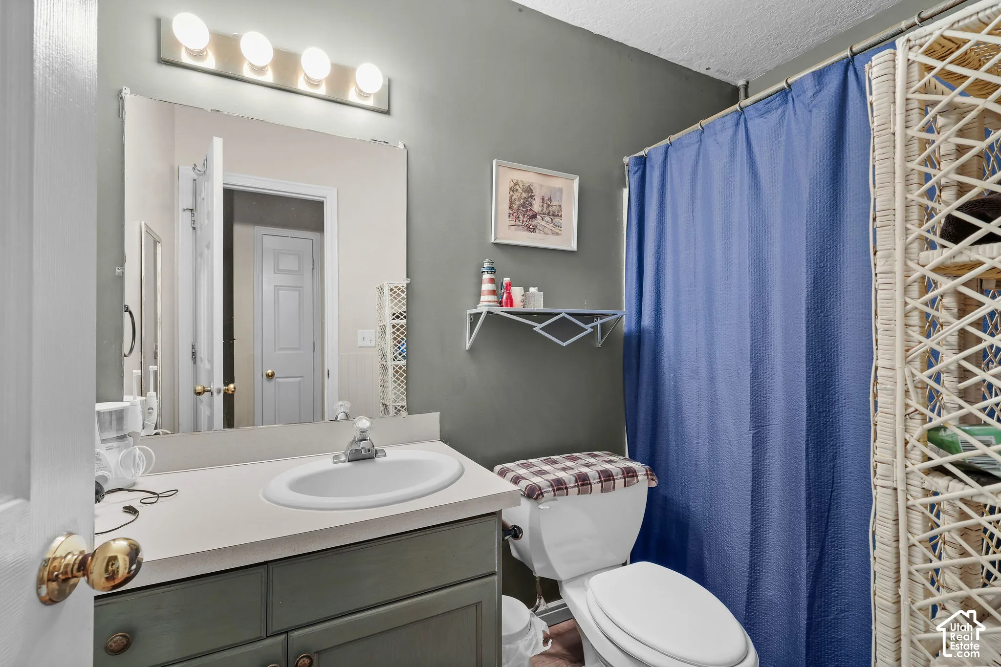 Vanity with integrated sink and chrome faucet, large wall-mounted mirror, and overhead four-bulb vanity light fixture