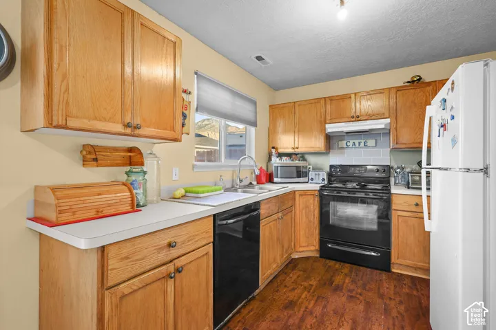 Unit B, Wood-finish cabinetry, solid surface countertops, a stainless steel sink, black range, and black dishwasher
