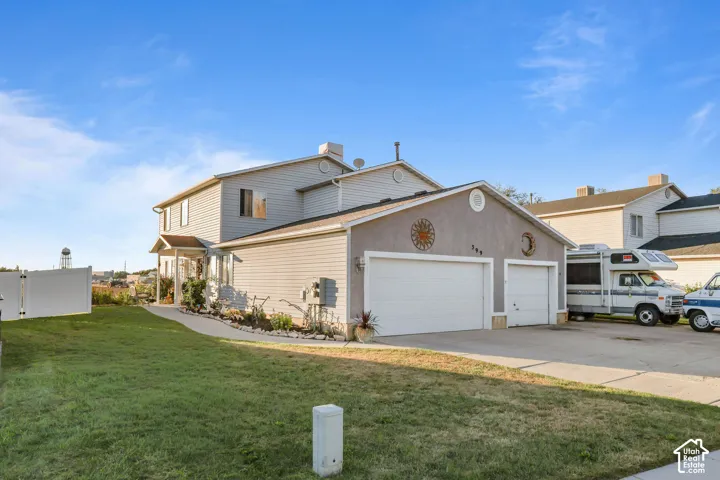 Two-story residence with a two-car garage, partial stucco and siding exterior, and a white fence