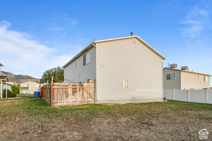 Siding exterior with multiple windows, featuring a gable roofline and a wooden fence