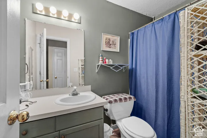 Vanity with integrated sink and chrome faucet, large wall-mounted mirror, and overhead four-bulb vanity light fixture