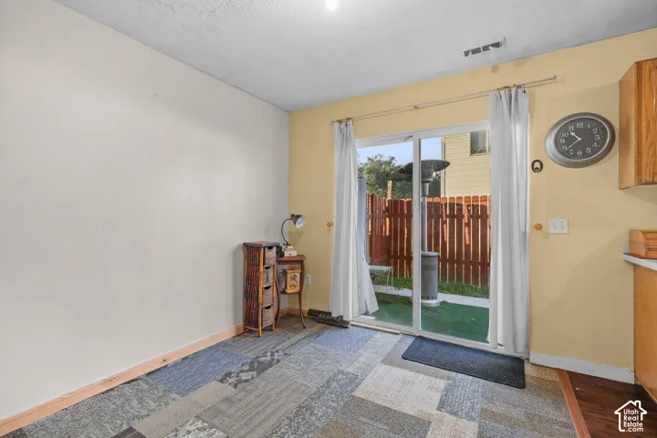Unit B, Sliding glass door, partial kitchen cabinetry, wood-finish flooring, and a privacy fence
