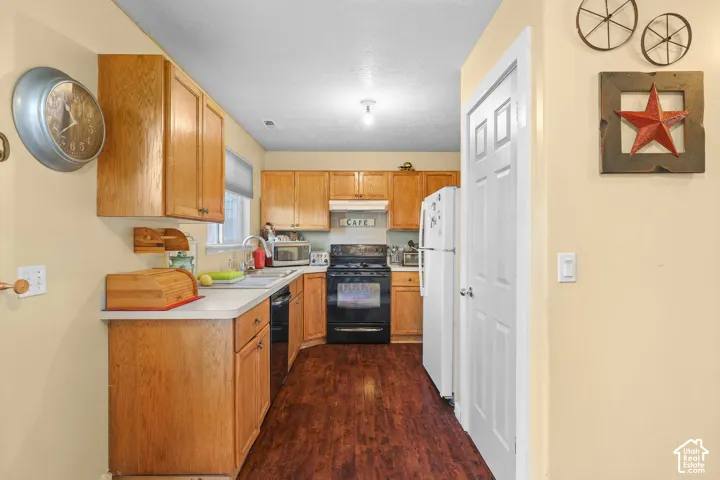 Unit B, Kitchen featuring wood cabinetry, white countertops, dark wood-finish flooring, and a black range