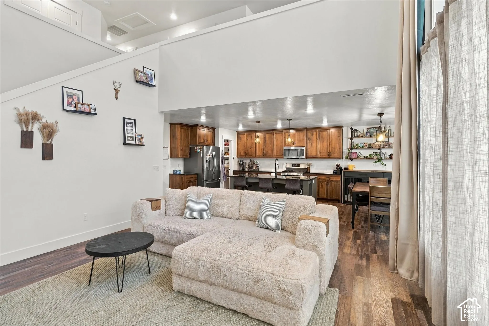 Open concept living area featuring wood-finish flooring, high ceilings, and a kitchen with wood cabinetry