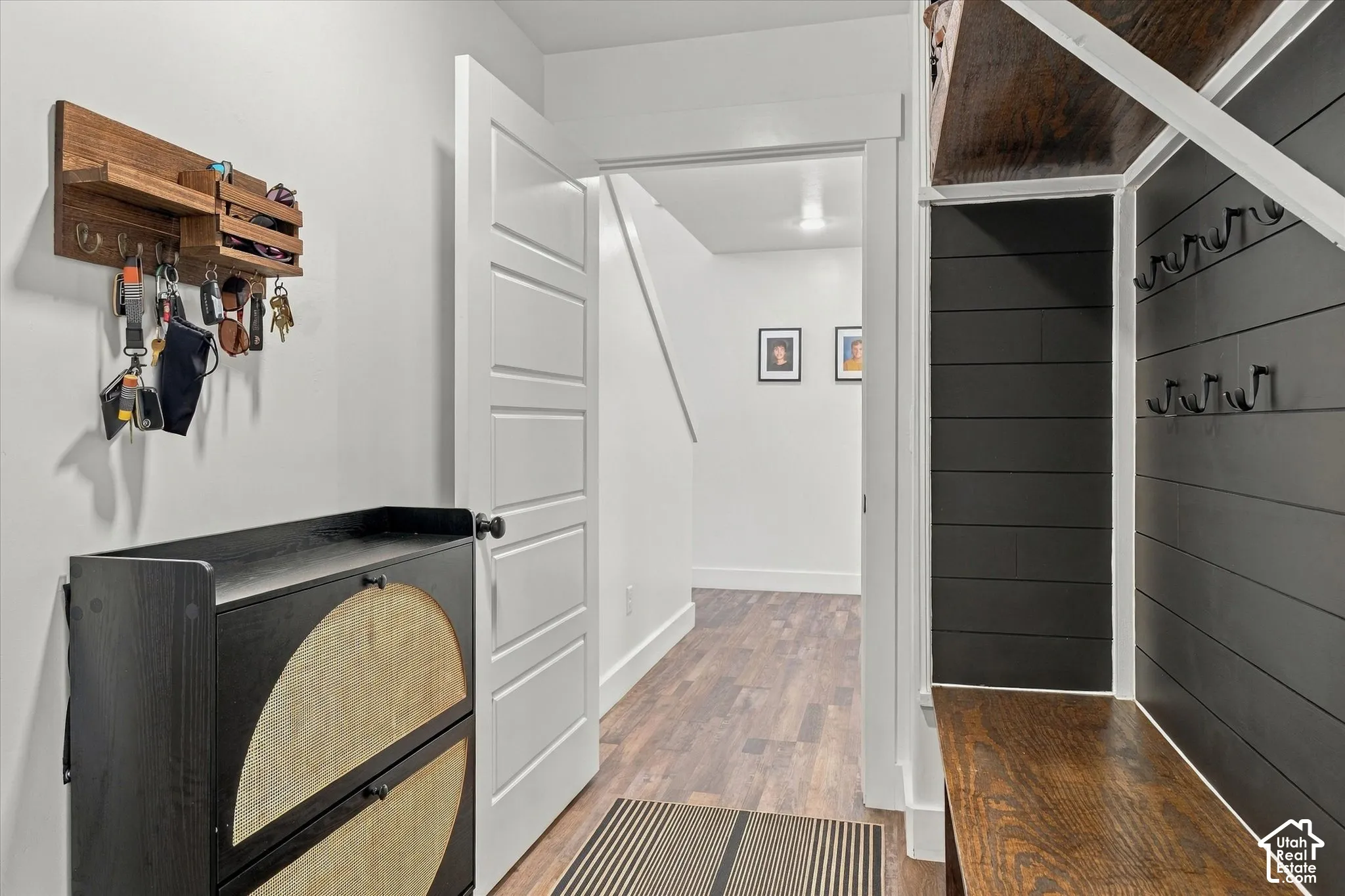 Built-in wood-finish bench with black shiplap paneling and wall hooks