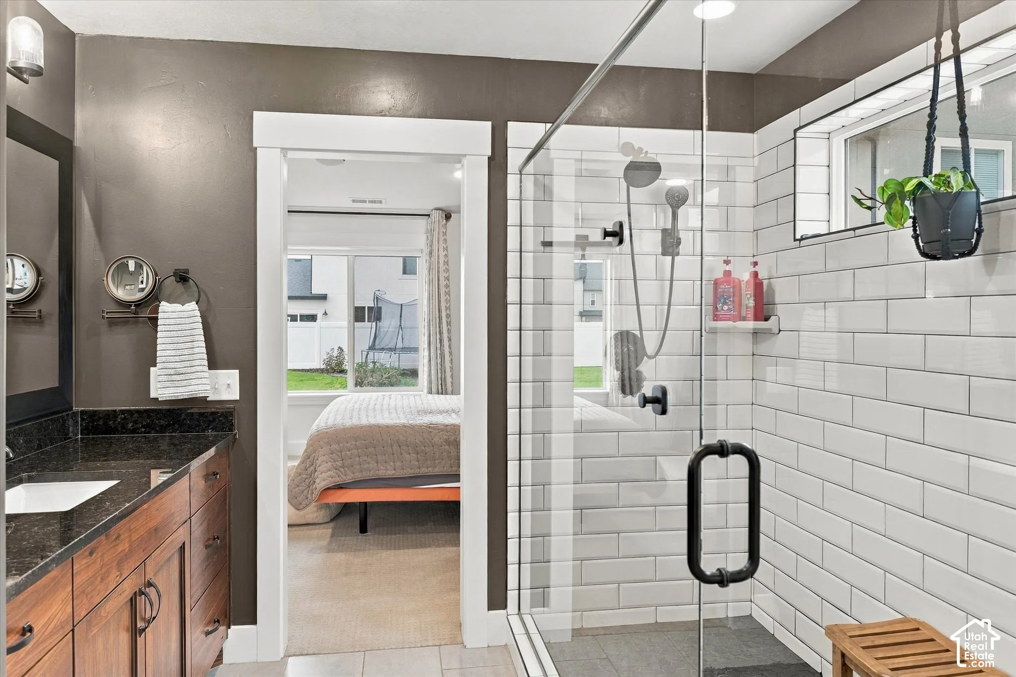 Glass-enclosed shower with white subway tile, dark-finish shower fixtures, and a transom window
