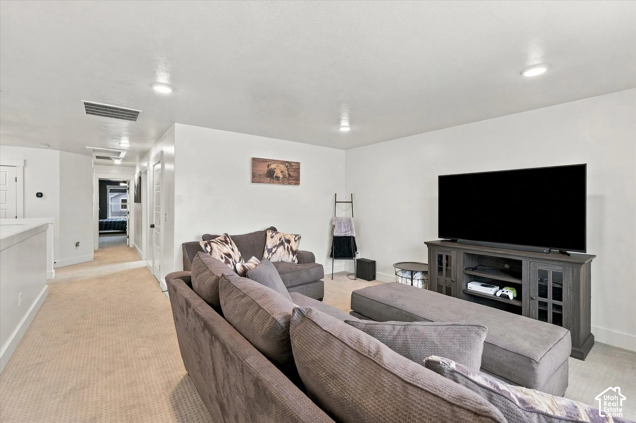 Recessed ceiling lighting, light-toned carpeting, white walls, and a hallway with additional lighting fixtures