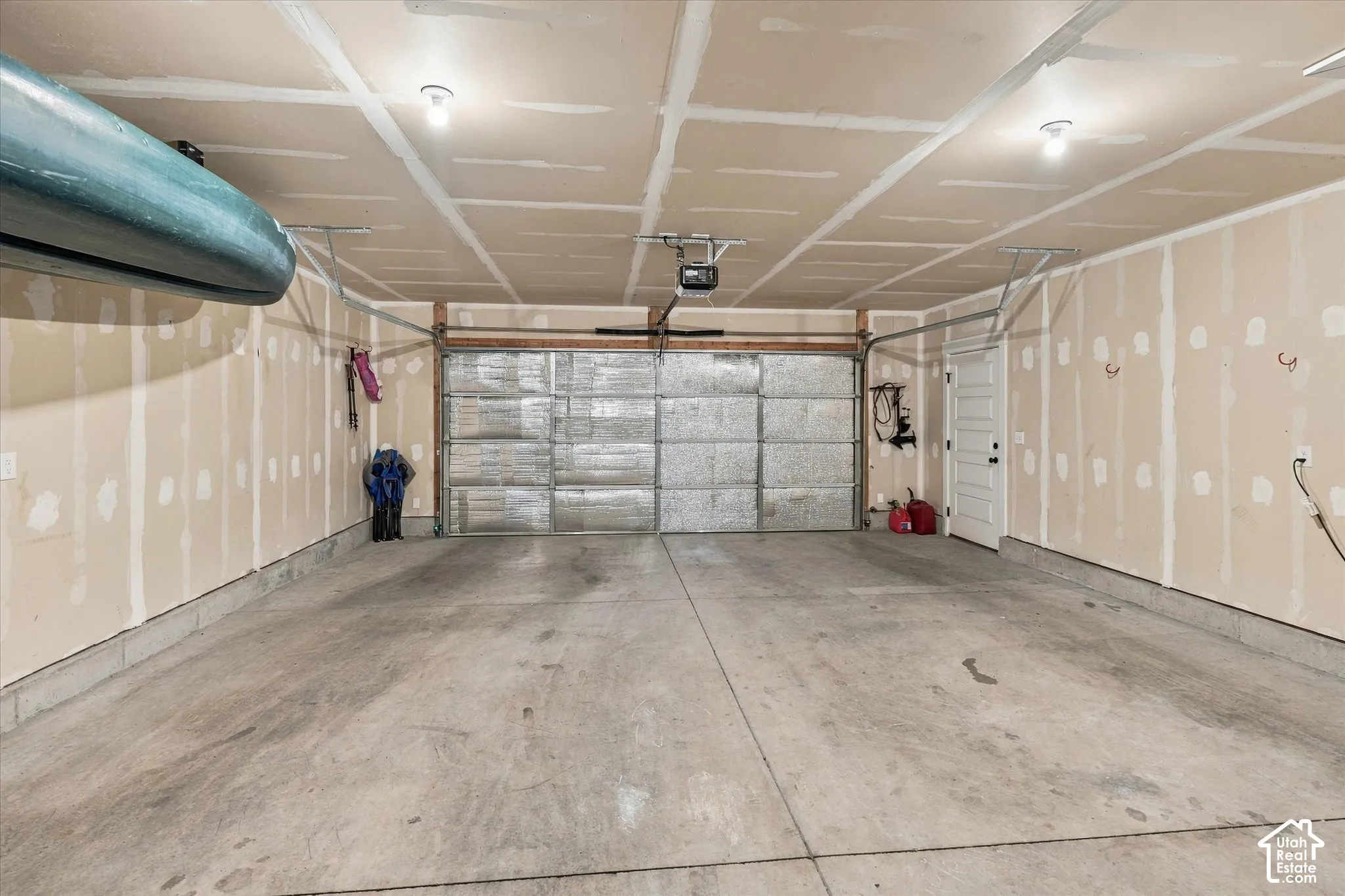 Spacious garage featuring a concrete floor, overhead lighting, and an automatic garage door opener