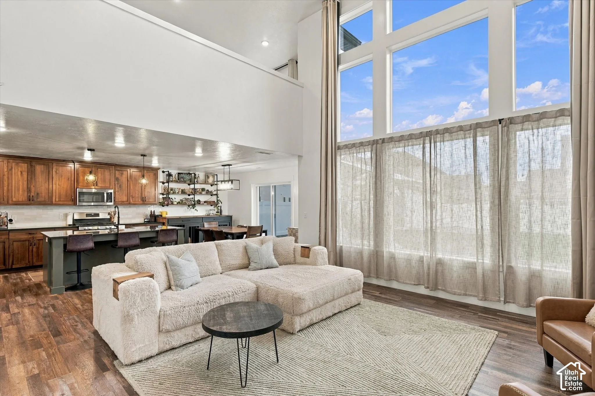 Open-concept living area featuring a kitchen with wood cabinetry, stainless steel appliances, and an island with bar seating